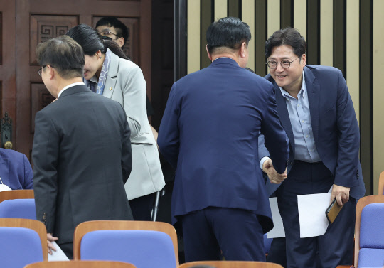 지난 20일 더불어민주당 차기 원내대표 선거 출마를 선언한 홍익표 의원(오른쪽)과 김두관 의원(가운데)이 국회에서 열린 의원총회에서 만나 악수를 나누고 있다. 연합뉴스.